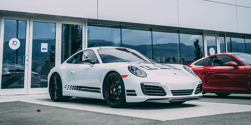 A white Porsche 911 outside a Porsche dealer.