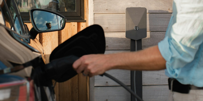 A man charges his car on a home charger.