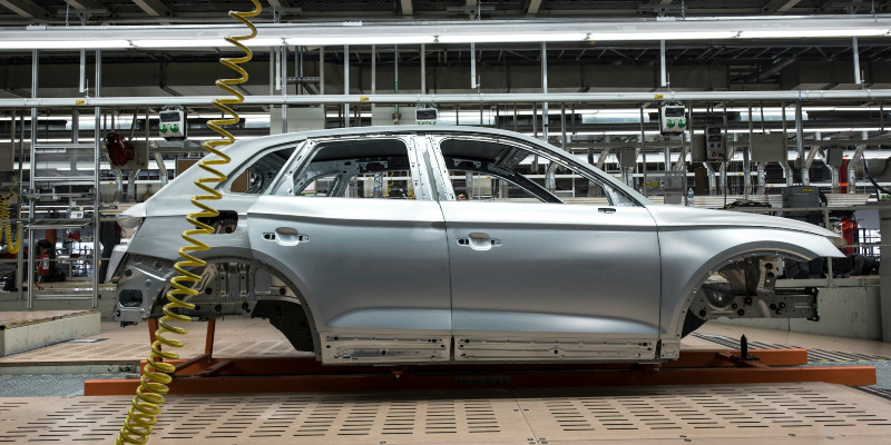 The frame of a car sits on a factory production line.
